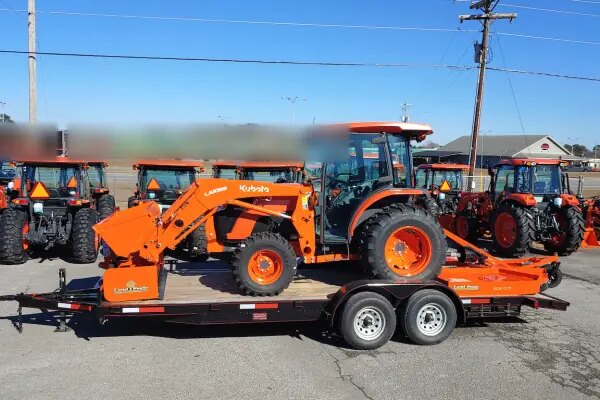 Orange compact tractor with loader secured on a trailer after a Kearney equipment recovery