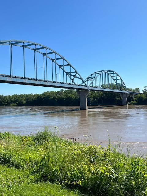 Steel arch bridge crossing a wide river beneath a clear blue sky