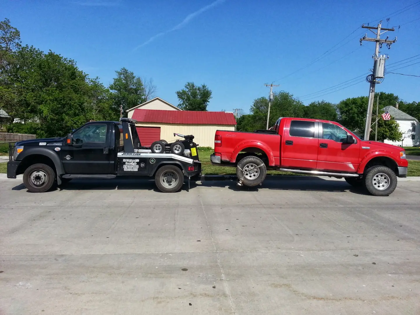 LRS self-loading tow truck connected to a red pickup during a daytime recovery in Mission Kansas
