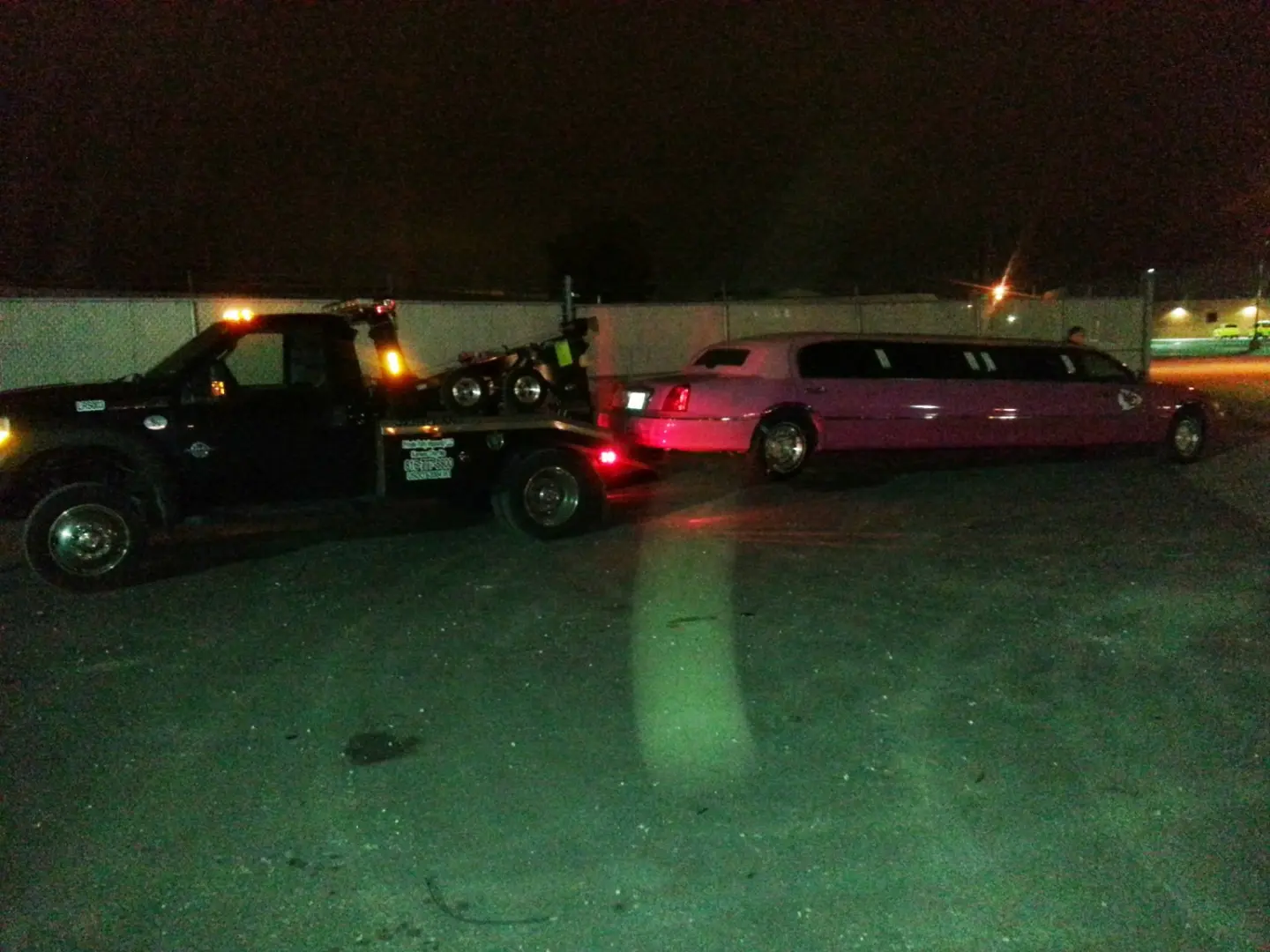 LRS wheel-lift tow truck positioned with a pink stretch limousine during a nighttime recovery in Mission Kansas